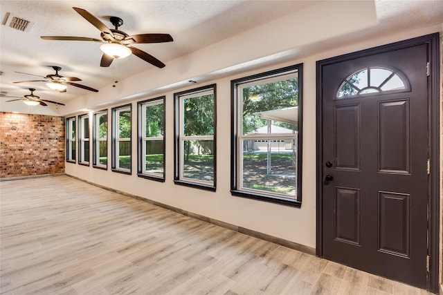 2004 Sleepy Hollow Dr, Pearland, TX 77581 - foyer featuring healthy amount of natural light, light wood-style flooring, a ceiling fan, brick wall, and a textured ceiling