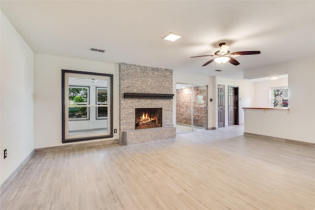 2004 Sleepy Hollow Dr, Pearland, TX 77581 - unfurnished living room with plenty of natural light, ceiling fan, light wood-style flooring, and a stone fireplace