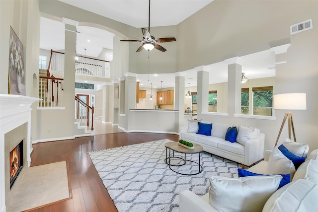 17422 Sunset Arbor Dr, Tomball, TX 77377 - living room featuring dark wood-style floors, ceiling fan, stairs, a towering ceiling, and a fireplace