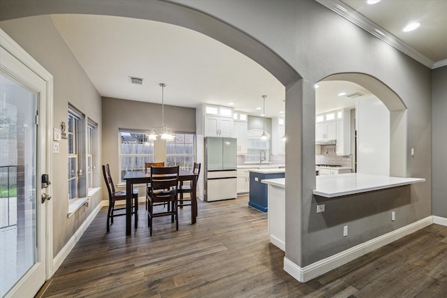 1611 Barrington Hills Ln, Katy, TX 77450 - dining space featuring dark wood-style flooring, crown molding, arched walkways, a chandelier, and recessed lighting