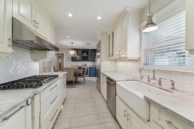 2603 Haverhill Dr, Houston, TX 77008 - kitchen with under cabinet range hood, stainless steel appliances, backsplash, recessed lighting, and glass insert cabinets