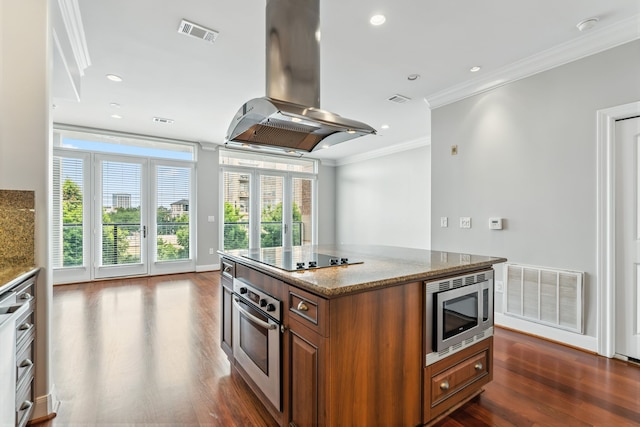 1419 Montrose Blvd Unit 301, Houston, TX 77019 - kitchen with stainless steel appliances, island range hood, brown cabinetry, dark wood finished floors, and ornamental molding