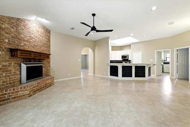 24806 Silver Leaf St, Magnolia, TX 77355 - unfurnished living room featuring a ceiling fan, light tile patterned floors, a fireplace, arched walkways, and recessed lighting