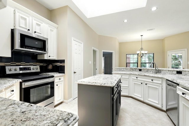 24806 Silver Leaf St, Magnolia, TX 77355 - kitchen with appliances with stainless steel finishes, white cabinetry, light tile patterned flooring, a chandelier, and tasteful backsplash
