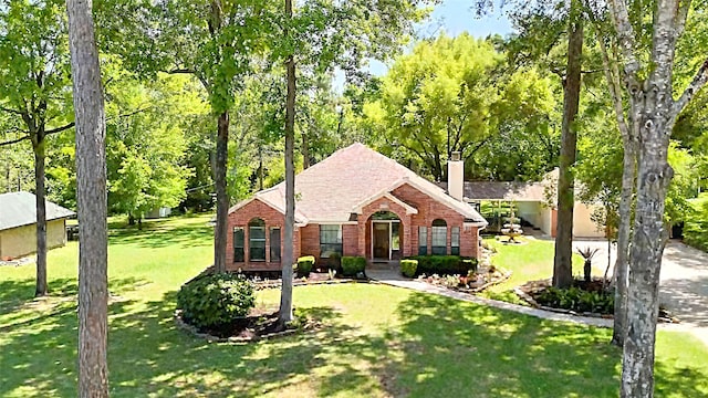 24806 Silver Leaf St, Magnolia, TX 77355 - view of front of house featuring brick siding, a front lawn, a chimney, and view of wooded area