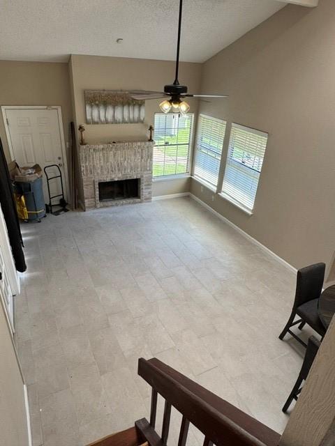 11957 Bob White Dr Unit 863, Houston, TX 77035 - unfurnished living room with a ceiling fan, a textured ceiling, and a brick fireplace