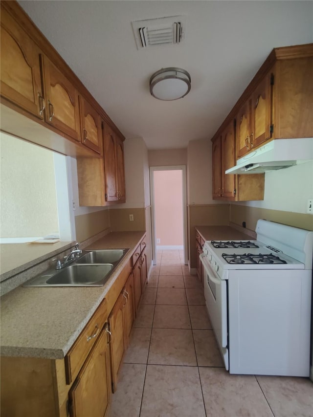 6714 Underhill St, Houston, TX 77092 - kitchen with white range with gas cooktop, under cabinet range hood, light countertops, brown cabinets, and light tile patterned floors