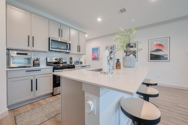 7822 Murciana Dr, Rosharon, TX 77583 - kitchen with appliances with stainless steel finishes, a breakfast bar, light wood-style flooring, light countertops, and recessed lighting