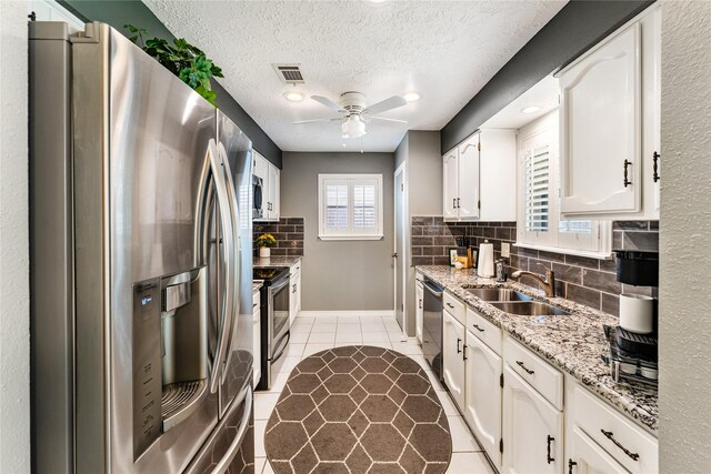 3426 Acorn Springs Ln, Spring, TX 77389 - kitchen with appliances with stainless steel finishes, a ceiling fan, backsplash, white cabinets, and light stone counters