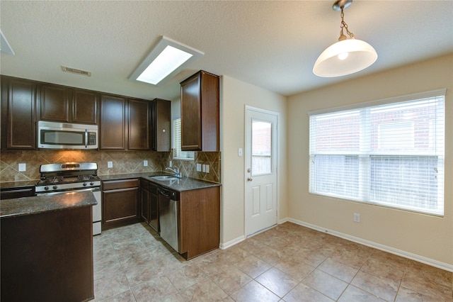 14839 Fir Knoll Way, Cypress, TX 77429 - kitchen featuring stainless steel appliances, backsplash, dark stone counters, decorative light fixtures, and dark brown cabinetry