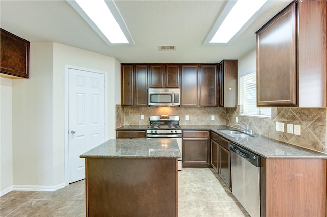 14839 Fir Knoll Way, Cypress, TX 77429 - kitchen with appliances with stainless steel finishes, stone counters, a kitchen island, tasteful backsplash, and dark brown cabinets