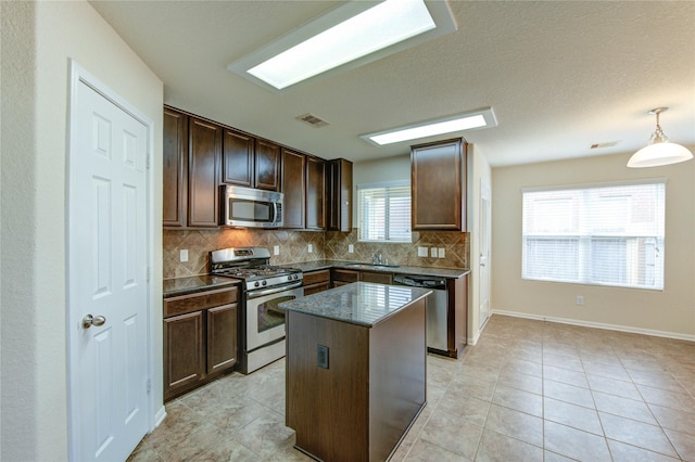 14839 Fir Knoll Way, Cypress, TX 77429 - kitchen featuring appliances with stainless steel finishes, tasteful backsplash, a kitchen island, dark brown cabinets, and light tile patterned flooring