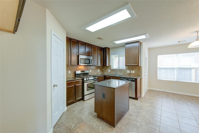 14839 Fir Knoll Way, Cypress, TX 77429 - kitchen with appliances with stainless steel finishes, decorative backsplash, a kitchen island, dark countertops, and light tile patterned flooring