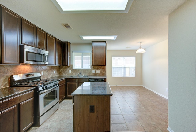 14839 Fir Knoll Way, Cypress, TX 77429 - kitchen featuring appliances with stainless steel finishes, backsplash, a kitchen island, dark stone counters, and dark brown cabinetry
