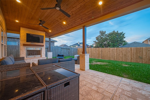 8134 Menorca Cove Dr, Cypress, TX 77433 - patio terrace at dusk with a patio, a fenced backyard, an outdoor living space with a fireplace, and a ceiling fan