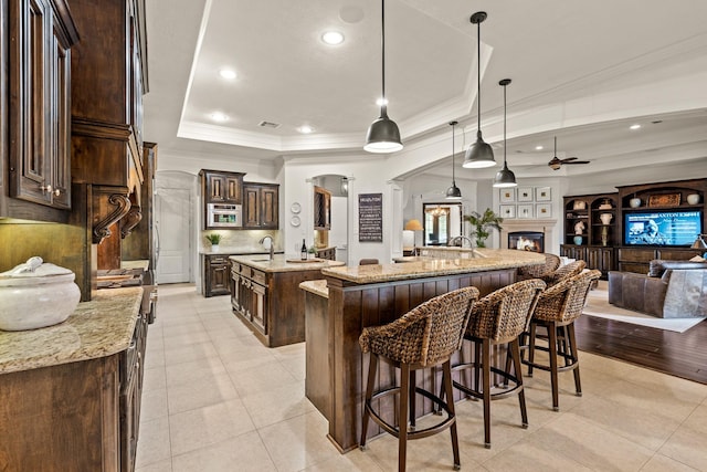 32723 Westminster Dr, Fulshear, TX 77441 - kitchen with a large island with sink, arched walkways, a raised ceiling, a ceiling fan, and open floor plan
