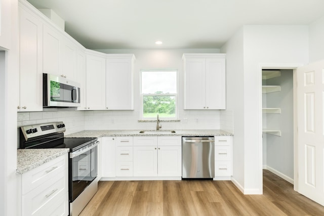 1927 Duncan Dr, Oyster Creek, TX 77541 - kitchen with stainless steel appliances, light wood-style floors, white cabinets, tasteful backsplash, and light stone counters