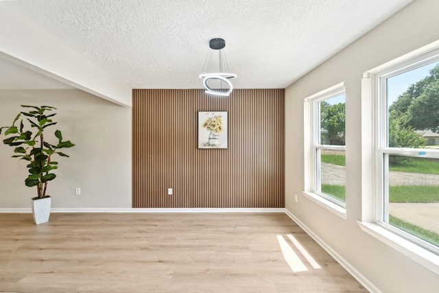 11114 Daybreak Ln, Cypress, TX 77429 - unfurnished dining area with light wood finished floors, plenty of natural light, a textured ceiling, and an accent wall