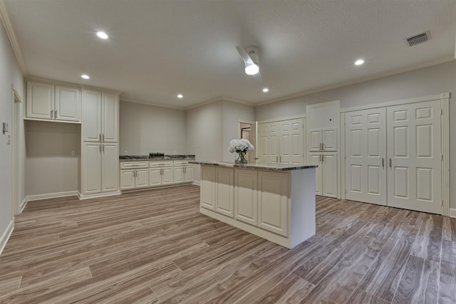 62 N Turtle Rock Ct, The Woodlands, TX 77381 - kitchen with ornamental molding, light wood-style floors, a kitchen island, recessed lighting, and white cabinetry