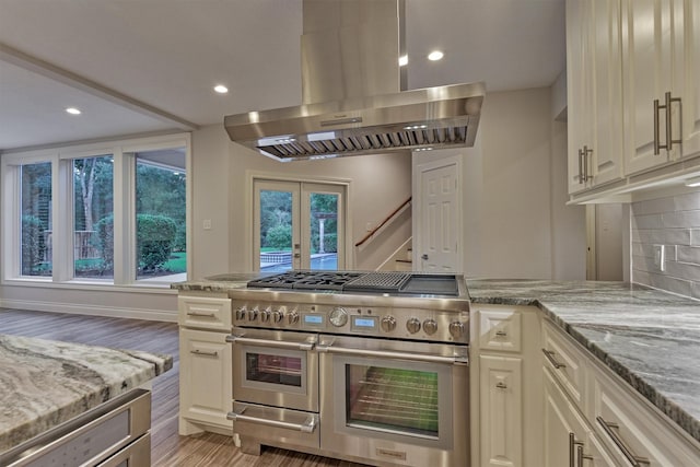 62 N Turtle Rock Ct, The Woodlands, TX 77381 - kitchen featuring range with two ovens, island exhaust hood, light wood-style flooring, light stone countertops, and french doors