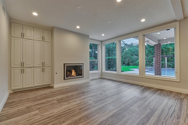 62 N Turtle Rock Ct, The Woodlands, TX 77381 - unfurnished living room with light wood finished floors, a glass covered fireplace, and recessed lighting