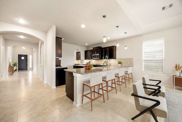 23414 Bracino Lake Dr, Katy, TX 77493 - kitchen featuring a kitchen breakfast bar, a peninsula, arched walkways, recessed lighting, and tasteful backsplash