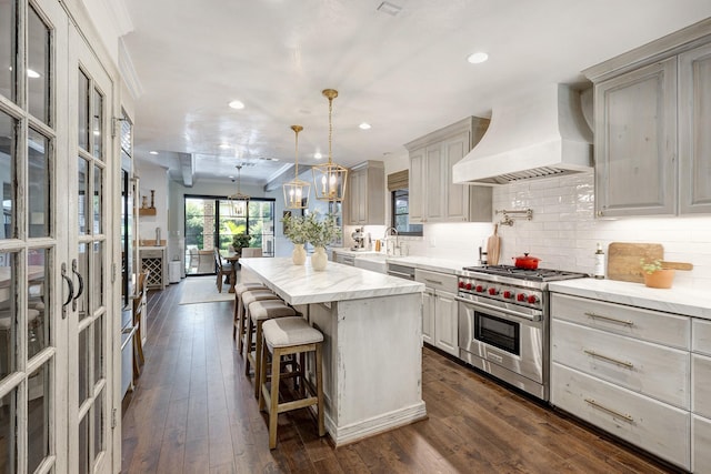 3739 University Blvd, Southside Place, TX 77005 - kitchen with designer stove, custom range hood, a center island, a breakfast bar, and tasteful backsplash