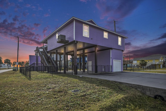23101 Camino St, Galveston, TX 77554 - back of property at dusk with stairway, an attached garage, and driveway