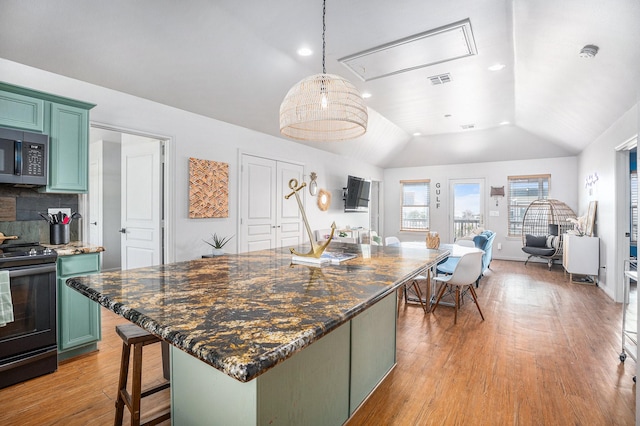 23101 Camino St, Galveston, TX 77554 - kitchen with green cabinetry, range with electric cooktop, stainless steel microwave, vaulted ceiling, and light wood-style flooring