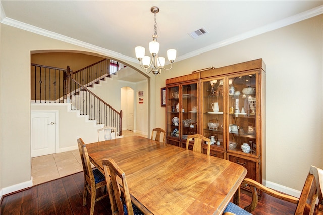 19723 Alton Springs Dr, Cypress, TX 77433 - dining space with arched walkways, a chandelier, ornamental molding, stairway, and dark wood-style flooring
