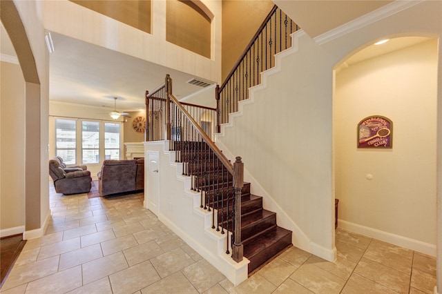 19723 Alton Springs Dr, Cypress, TX 77433 - stairs featuring ornamental molding, a ceiling fan, a fireplace, tile patterned flooring, and arched walkways