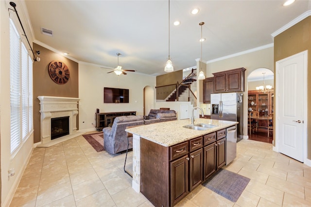 19723 Alton Springs Dr, Cypress, TX 77433 - kitchen with arched walkways, appliances with stainless steel finishes, a fireplace with raised hearth, crown molding, and a ceiling fan