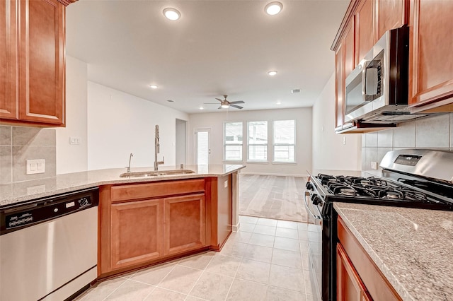 18822 Fulvetta Haven Way, Richmond, TX 77407 - kitchen with stainless steel appliances, a peninsula, light tile patterned flooring, light stone countertops, and recessed lighting