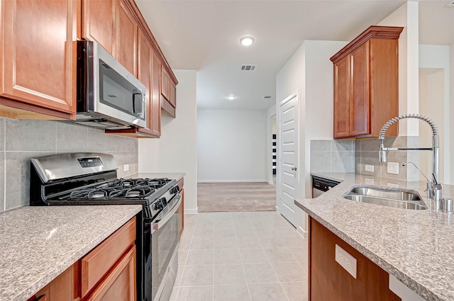18822 Fulvetta Haven Way, Richmond, TX 77407 - kitchen featuring appliances with stainless steel finishes, light stone countertops, tasteful backsplash, brown cabinets, and recessed lighting