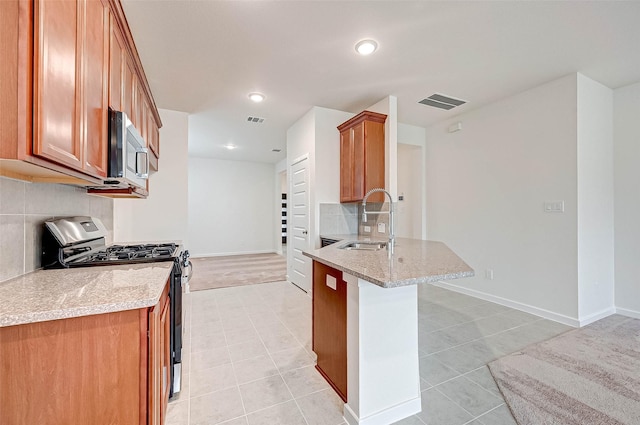 18822 Fulvetta Haven Way, Richmond, TX 77407 - kitchen featuring appliances with stainless steel finishes, backsplash, light tile patterned floors, brown cabinetry, and a peninsula