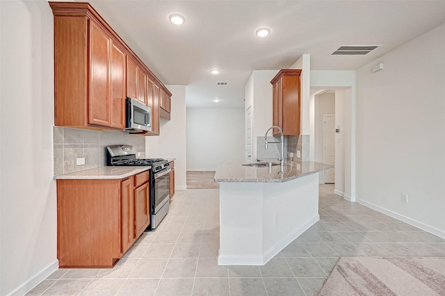 18822 Fulvetta Haven Way, Richmond, TX 77407 - kitchen featuring appliances with stainless steel finishes, backsplash, light tile patterned floors, a peninsula, and brown cabinetry