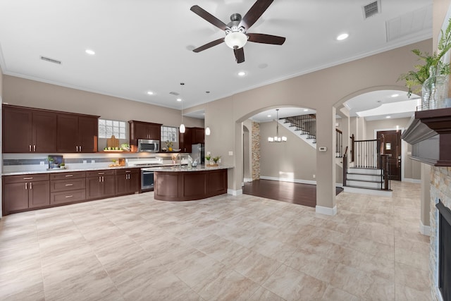 127 Benjis Pl, The Woodlands, TX 77380 - kitchen with stainless steel appliances, light countertops, ceiling fan, open floor plan, and a fireplace