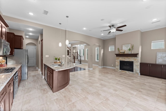 127 Benjis Pl, The Woodlands, TX 77380 - kitchen with arched walkways, stainless steel appliances, ceiling fan, a stone fireplace, and recessed lighting