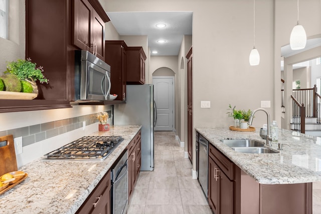 127 Benjis Pl, The Woodlands, TX 77380 - kitchen featuring stainless steel appliances, tasteful backsplash, arched walkways, decorative light fixtures, and light stone countertops