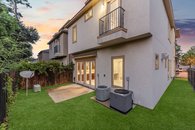 127 Benjis Pl, The Woodlands, TX 77380 - back of property at dusk featuring a balcony, a fenced backyard, stucco siding, and a patio
