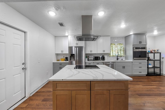 5413 Bataan Rd, Houston, TX 77033 - kitchen featuring stainless steel appliances, wall chimney exhaust hood, tasteful backsplash, dark wood finished floors, and a textured ceiling