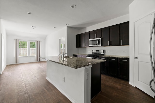 20213 Portbec Dr, New Caney, TX 77357 - kitchen with stainless steel appliances, dark wood-style flooring, dark stone counters, a kitchen island with sink, and recessed lighting