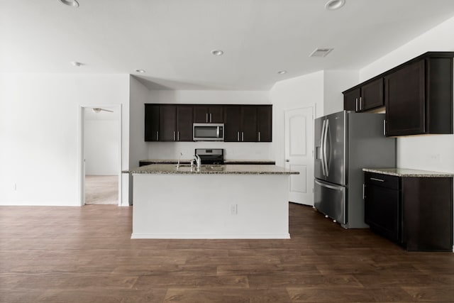 20213 Portbec Dr, New Caney, TX 77357 - kitchen with stainless steel appliances, light stone counters, a kitchen island with sink, recessed lighting, and dark wood finished floors
