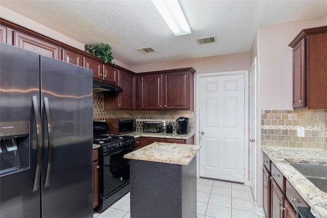 1526 Daffodil Rd, Missouri City, TX 77489 - kitchen with fridge with ice dispenser, black gas stove, under cabinet range hood, light tile patterned floors, and backsplash