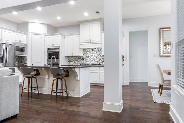 29110 Davenport Dr, Katy, TX 77494 - kitchen with appliances with stainless steel finishes, a kitchen breakfast bar, dark countertops, decorative backsplash, and recessed lighting