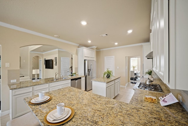 5706 Jenolan Ridge Ln, Sugar Land, TX 77479 - kitchen with stainless steel appliances, a center island, arched walkways, crown molding, and light stone countertops
