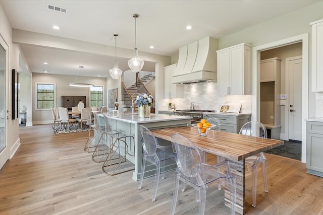 1710 Ebony Ln, Houston, TX 77018 - kitchen featuring custom exhaust hood, high end stainless steel range, backsplash, light wood-style floors, and recessed lighting