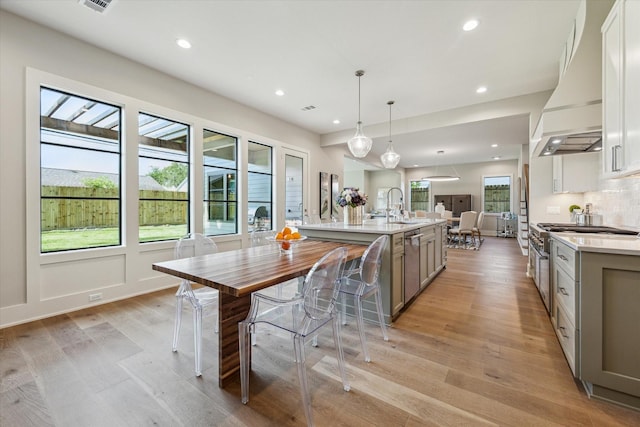 1710 Ebony Ln, Houston, TX 77018 - kitchen featuring custom range hood, light countertops, a spacious island, light wood-style flooring, and recessed lighting