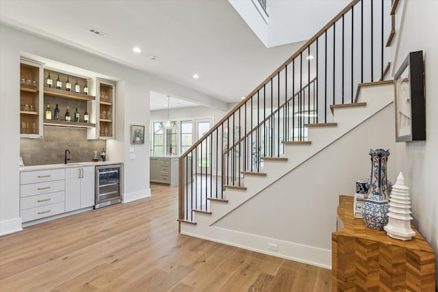 1710 Ebony Ln, Houston, TX 77018 - indoor wet bar featuring wine cooler, stairs, light wood-style floors, tasteful backsplash, and recessed lighting