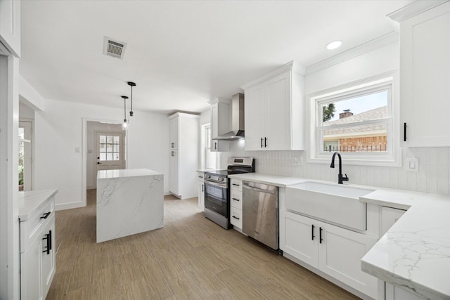 9711 Braewick Dr, Houston, TX 77096 - kitchen with stainless steel appliances, wall chimney exhaust hood, light wood-style flooring, white cabinetry, and recessed lighting